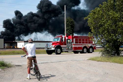 A resident watches as a firetruck arrives in downtown Dupo, Ill. to help fight a tanker fire from a derailed train on Tuesday, Sept. 10. 2019. Black smoke coming from the derailment scene can be seen for miles and caused the evacuation of schools in the town, authorities said.