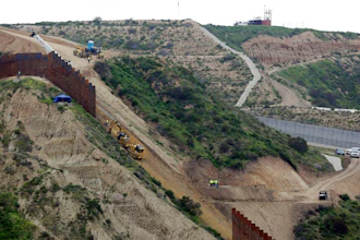 In this March 11, 2019 photo, construction crews replace a section of the primary wall separating San Diego, above right, and Tijuana, Mexico, below left, seen from Tijuana, Mexico. Defense Secretary Mark Esper has approved the use of $3.6 billion in funding from military construction projects to build 175 miles of President Donald Trump’s wall along the Mexican border.