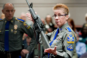 In this Jan. 28, 2013, file photo, firearms training unit Det. Barbara J. Mattson, of the Connecticut State Police, holds up a Bushmaster AR-15 rifle, the same make and model of gun used by Adam Lanza in the Sandy Hook School shooting, for a demonstration during a hearing of a legislative subcommittee reviewing gun laws