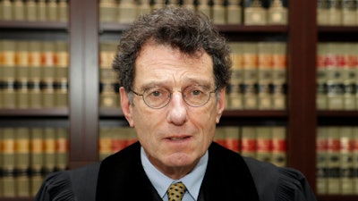 This Jan. 11, 2018 file photo shows Judge Dan Polster in his office, in Cleveland. Attorneys representing eight drug distributors, pharmacies and retailers facing trial for their roles in the national opioid crisis are seeking to disqualify the federal judge overseeing their cases saying he’s shown clear bias in his efforts to obtain a multi-billion dollar global settlement. The motion was filed late Friday, Sept. 13, 2019, in U.S. District Court in Cleveland, where Judge Dan Polster presides over most of the 2,000 lawsuits filed by state, local and tribal governments. Polster has not responded.