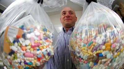 Narcotics detective Ben Hill, with the Barberton Police Department, shows two bags of medications that are are stored in their headquarters and slated for destruction, Wednesday, Sept. 11, 2019, in Barberton, Ohio. Attorneys representing some 2,000 local governments said Wednesday they have agreed to a tentative settlement with OxyContin maker Purdue Pharma over the toll of the nation's opioid crisis.