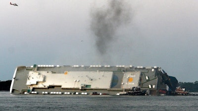 In this Sunday, Sept. 8, 2019 photo, smoke rises from a cargo ship that capsized in the St. Simons Island, Ga., sound. Authorities say oil from an overturned cargo ship has reached several parts of Georgia’s shoreline, leaving a sheen in marshes and oiled debris on beaches.