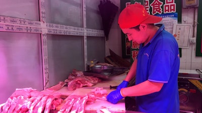 A butcher slices cuts of pork at a meat market in Beijing.