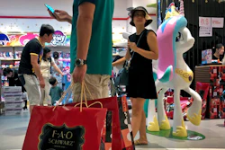 In this June 1, 2019, photo, file a man carries a paper bags containing toys purchased from the FAO Schwarz as people shop at the newly open FAO Schwarz toy store at the capital city's popular shopping mall in Beijing. Caught in the crossfire of a trade war, American businesses operating in the China say they’ve been hurt by the hostilities between the world’s two biggest economies and are facing increasingly unfair competition from Chinese firms.