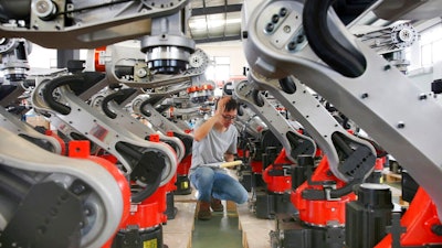 In this Wednesday, Sept. 11, 2019, photo, a man checks on the robotic arms at a factory making industrial robots in Zhengyu town of Haimen city in east China's Jiangsu province. A Chinese envoy is going to Washington on Wednesday, Sept. 18, to prepare for trade negotiations. The announcement Tuesday, Sept. 17, follows conciliatory gestures by both sides ahead of the October talks on their fight over trade and technology, which threatens to dampen global economic growth.