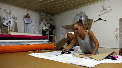 In this Wednesday, Sept. 4, 2019 photo, a seamstress works on a piece of white silk at Zeus+Dione atelier in Athens. Greece's financial crisis nearly snuffed out the country's centuries-old silk manufacturing tradition, but the end of the crippling recession has raised demand for fashion products and silk produced by a remote border town.