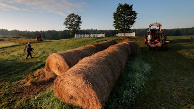 Dairy farmer Fred Stone walks to his baling machine at his dairy farm in Arundel, Maine.