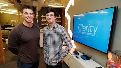 In this Tuesday, Sept. 10, 2019, photo Shane Griffiths, right, and Trenton Erker, left, co-owners of the digital marketing company Clarity Online, pose for a photo in Seattle. Griffiths and Erker use technology for tasks like billing, scheduling appointments, tracking the time they spend on clients' projects and putting together reports on visits to client websites, as well as using freelancers for other tasks as ways to save money on employment costs, and also have more flexibility when they need specific talents or expertise for a project.