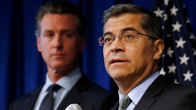 In this Sept. 18, 2019 file photo California Attorney General Xavier Becerra, right, flanked by Gov. Gavin Newsom, discusses the Trump administration's pledge to revoke California's authority to set vehicle emissions standards that are different than the federal standards, during a news conference in Sacramento, Calif. Twenty-three states have sued to stop the Trump administration from revoking California's authority to set emission standards for cars and trucks. Becerra is leading the lawsuit filed Friday, Sept. 20 along with Newsom and the California Air Resources Board.