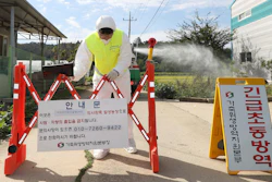 A quarantine official wearing protective gear places a barricade as a precaution against African swine fever at a pig farm in Paju, South Korea.