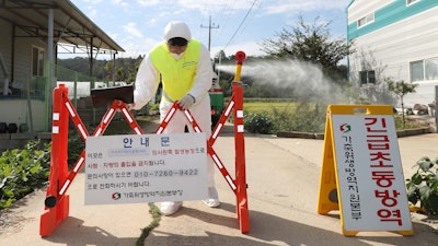 A quarantine official wearing protective gear places a barricade as a precaution against African swine fever at a pig farm in Paju, South Korea.