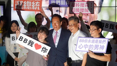 In this June 21, 2019, file photo, Terry Gou, center, chairman of Foxconn, the world's largest contract assembler of consumer electronics, poses with supporters for a photo after the company's annual shareholders meeting in New Taipei City, Taiwan. Gou has given up on making a bid for Taiwan's presidency. Gou announced his decision in a statement late Monday, Sept. 16, 2019, one day before a deadline to register for the race.