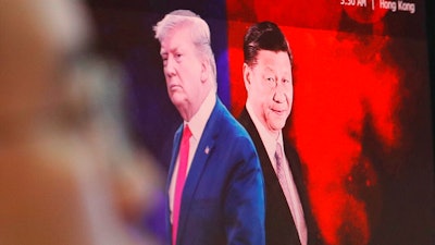 In this Aug. 26, 2019, file photo, a computer screen shows images of Chinese President Xi Jinping, right, and U.S. President Donald Trump as a currency trader works at the foreign exchange dealing room of the KEB Hana Bank headquarters in Seoul, South Korea. China will lift punitive tariffs imposed on U.S. soybeans and pork in a trade war with Washington, a state news agency said Friday, Sept. 13, 2019, in a possible goodwill gesture ahead of negotiations.