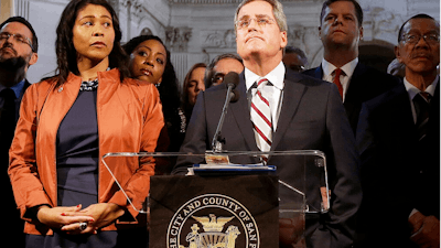 In this Dec. 12, 2017 file photo, city attorney Dennis Herrera, center, speaks at a news conference next to acting mayor London Breed, left, at City Hall in San Francisco. San Francisco officials are offering to buy Pacific Gas & Electric's power lines and other infrastructure in the city for $2.5 billion. Mayor London Breed and City Attorney Dennis Herrera presented the offer in a letter sent to the utility Friday, Sept. 6, 2019.