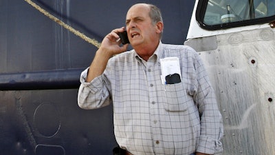 In this Oct. 14, 2014, file photo, Carlos Rafael talks on the phone at Homer's Wharf near his herring boat F/V Voyager in New Bedford, Mass. Rafael was sentenced to prison in 2017 after pleading guilty to evading fishing quotas and smuggling profits overseas. A father-and-son team from Massachusetts and other buyers are acquiring scallop fishing boats owned by the disgraced fishing magnate nicknamed the Codfather. The sale of Rafael’s 11 scallop boats and their related permits signals the beginning of his forced divestment from U.S. fisheries. The federal government is making the imprisoned Rafael sell his fishing assets as part of a civil settlement.