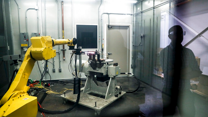 In this May 18, 2017, file photo, a robotic arm with a high-intensity blowtorch is remotely operated to test ceramic matrix composites, which make engines more durable, heat-resistant and efficient, at the General Electric Aviation plant in Evendale, Ohio. General Electric Co. said Monday, Oct. 7, 2019, that it will freeze its pension plan for about 20,700 salaried workers as part of its debt-cutting plan.