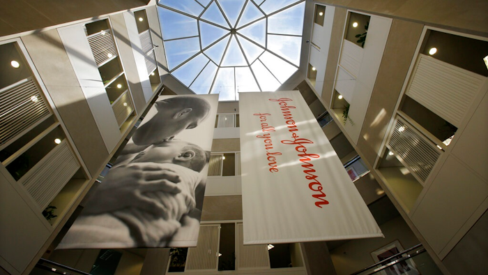 In this July 30, 2013, file photo, large banners hang in an atrium at the headquarters of Johnson & Johnson in New Brunswick, N.J. Johnson & Johnson has become the latest company to settle a lawsuit to get out of the first federal trial over the nation's opioids crisis, reaching a deal worth more than $20 million with two Ohio counties, the company announced Tuesday, Oct. 1, 2019.