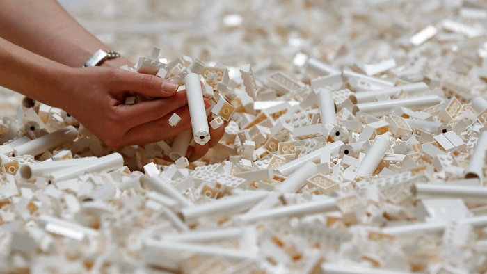 In this Friday July 26, 2019, file photo, a visitor looks through Lego pieces provided for a project at the Tate Modern, in London. Lego is testing a way for customers to ship their unwanted bricks back and get them into the hands of other kids.