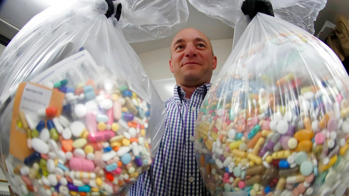 In this Wednesday, Sept. 11, 2019, file photo, narcotics detective Ben Hill, with the Barberton Police Department, shows two bags of medications that are are stored in their headquarters and slated for destruction in Barberton, Ohio. Jury selection is set to begin Wednesday, Oct. 16, 2019, in the first federal trial over the nation's opioid epidemic.