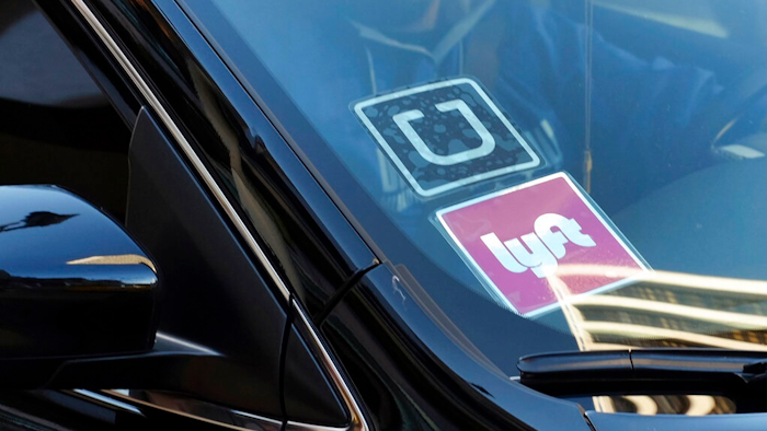 In this Jan. 12, 2016, file photo, a ride share car displays Lyft and Uber stickers on its front windshield in downtown Los Angeles. Members of Congress are asking ride-hailing companies Uber and Lyft to improve safety and clean up their act. They introduced a bill that would help riders confirm that a driver is legitimate and not a fake driver hoping to do harm.
