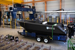 In this Wednesday, Oct. 9, 2019 photo provided by the University of Maine, a 25-foot, 5,000-pound patrol boat, center, that was produced using a large polymer 3D printer, behind left, rests on a trailer on the school's campus, in Orono, Maine. The boat was printed at the school's Composites Center on the world's largest polymer 3D printer.
