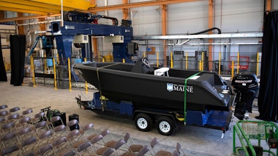 In this Wednesday, Oct. 9, 2019 photo provided by the University of Maine, a 25-foot, 5,000-pound patrol boat, center, that was produced using a large polymer 3D printer, behind left, rests on a trailer on the school's campus, in Orono, Maine. The boat was printed at the school's Composites Center on the world's largest polymer 3D printer.