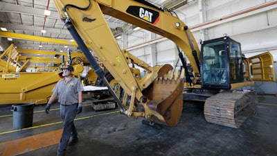 In this Sept. 18, 2019 photo, a Puckett Machinery Company technician walks past a new heavy duty Caterpillar excavator that awaits modification at Puckett Machinery Company in Flowood, MS.