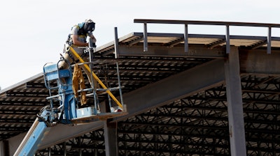 This July 1, 2019, photo shows a construction worker atop a new building in Hillsborough, N.C.