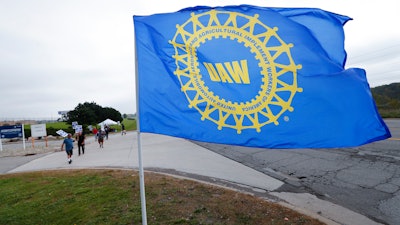 In this Sept. 30 photo, a UAW flag flies near strikers outside the General Motors Orion Assembly plant in Orion Township, MI.