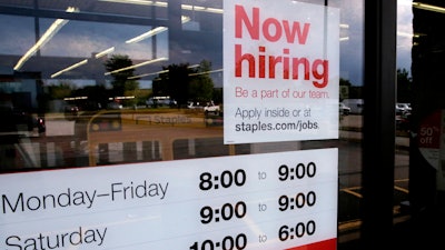 n this Aug. 15, 2019 file photo, a 'Now hiring' sign is displayed on the front door of a Staples store in Manchester, NH.