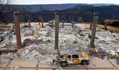 In this Dec. 3, 2018 file photo, a vehicle rests in front of a home leveled by the Camp Fire in Paradise, CA. Two years to the day after some of the deadliest wildfires tore through Northern California wine country, two of the state's largest utilities were poised Tuesday, Oct. 8, 2019, to shut off power to more than 700,000 customers in 37 counties, in what would be the largest preventive shut-off to date as utilities try to head off wildfires caused by faulty power lines.