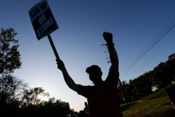 A member of the United Auto Workers cheers on honking cars as he walks the picket line at the General Motors Romulus Powertrain plant in Romulus, MI on Oct. 9.