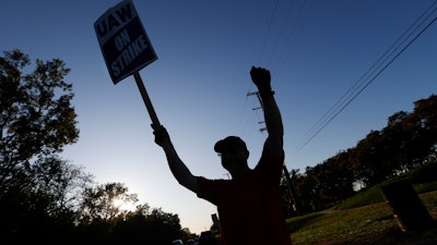 A member of the United Auto Workers cheers on honking cars as he walks the picket line at the General Motors Romulus Powertrain plant in Romulus, MI on Oct. 9.