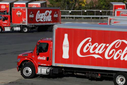 In this Monday, Oct. 14 photo, a truck with the Coca-Cola logo, behind left, maneuvers in a parking lot at a bottling plant in Needham, MA.