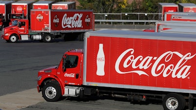 In this Monday, Oct. 14 photo, a truck with the Coca-Cola logo, behind left, maneuvers in a parking lot at a bottling plant in Needham, MA.