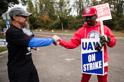 Picketing United Auto Workers Richard Rivera, left, and Will Myatt react to news of a tentative contract agreement with General Motors, in Langhorne, PA on Wednesday.