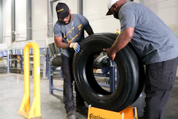 Travis Chambliss, left, and Jason Wallace unload the first tire produced at the Clinton Continental Tire Plant from a conveyor belt during the Continental Tire Grand Opening in Clinton, MS on Wednesday, Oct. 16.