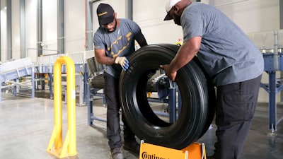 Travis Chambliss, left, and Jason Wallace unload the first tire produced at the Clinton Continental Tire Plant from a conveyor belt during the Continental Tire Grand Opening in Clinton, MS on Wednesday, Oct. 16.