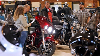 In this Oct. 17, 2019 file photo customers look over Harley Davidson motorcycles on display at a dealership in Ashland, VA.