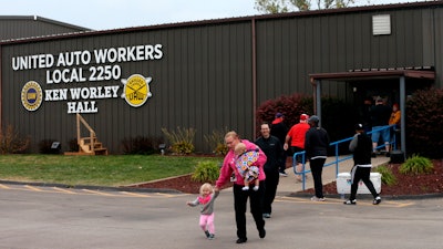 United Auto Worker Lindsey Higgins, exits the the UAW Local 2250 Ken Worley Hall with her two children after voting on the offer made to union workers by General Motors on Thursday, Oct. 24, in Wentzville, MO.