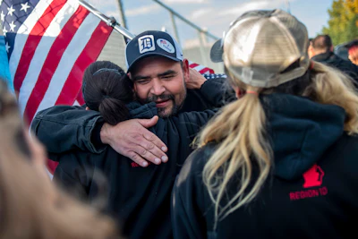 Saginaw resident Michael Perez and other members celebrate during the 40th and final day of the United Auto Workers strike against General Motors outside of the Flint Assembly Plant on Frida in Flint, MI.