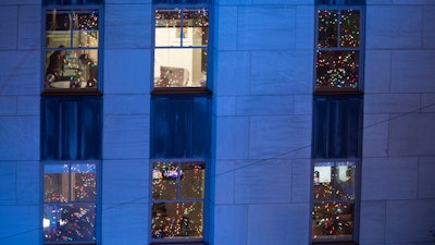 In this Nov. 28, 2018 file photo, people work in their office after the Rockefeller Center Christmas tree is lit during the 86th annual Rockefeller Center Christmas tree lighting ceremony in New York.