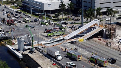 In this March 15, 2018, file photo, emergency personnel respond after a brand-new pedestrian bridge collapsed onto a highway at Florida International University in Miami. Federal officials have determined the Miami university bridge that collapsed and killed six people showed significant design errors and the state government should have conducted greater oversight because of the project’s complexity. National Transportation Safety Board members concluded Tuesday, Oct. 22, 2019, the design firm FIGG Bridge Engineers, Inc. underestimated the load of the bridge and overestimated its strength in a critical section that splintered, dropping a 174-foot-long (53-meter) span onto eight cars.