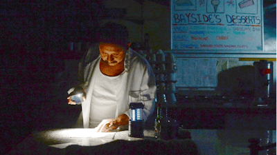 Carlos Lama of Bayside Cafe, which was among businesses to lose power due to PG&E's public safety power shutoff, uses an LED lamp and light from his phone at the counter of the restaurant in Sausalito, Calif., Wednesday, Oct. 9, 2019. More than a million people in California were without electricity Wednesday as the state's largest utility pulled the plug to prevent a repeat of the past two years when windblown power lines sparked deadly wildfires that destroyed thousands of homes.