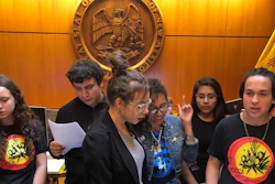 High school student Artemisio Romero y Carver, right, of Santa Fe, leads environmental activists in a climate change protest song as they deliver a letter of demands to the office of New Mexico Gov. Michelle Lujan Grisham.