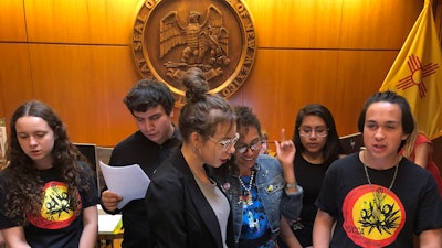 High school student Artemisio Romero y Carver, right, of Santa Fe, leads environmental activists in a climate change protest song as they deliver a letter of demands to the office of New Mexico Gov. Michelle Lujan Grisham.