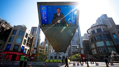 In this April 26, 2019, file photo, traffic warden and securities stand guard near a TV screen broadcasting live of President Xi Jinping's opening speech, outside a shopping mall in Beijing. Companies who do business with China walk a fine line to stay aligned with U.S. values such as freedom of speech and democracy while avoiding offending China, where they stand to make billions of dollars.