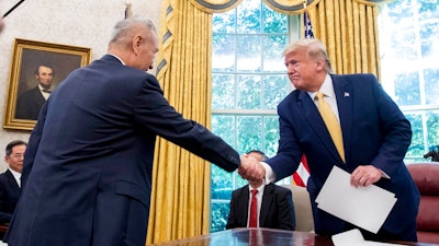 In this Oct. 11, 2019, file photo, U.S. President Donald Trump, right, shakes hands with Chinese Vice Premier Liu He after being given a letter in the Oval Office of the White House in Washington. China's trade with the United States fell by double digits again in September amid a tariff war that threatens to tip the global economy into recession.
