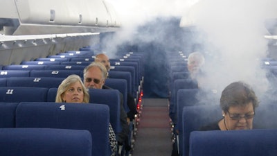 FAA employees participate in a demonstration of an airline cabin filling with smoke, in a simulator at the FAA Civil Aerospace Medical Institute in the Mike Monroney Aeronautical Center, Thursday, Oct. 17, 2019, in Oklahoma City. Federal researchers, using 720 volunteers in Oklahoma City, will test whether smaller seats and crowded rows slow down airline emergency evacuations.