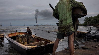 Fishermen covered in oil get their boat ready for fishing on Lake Maracaibo near La Salina crude oil shipping terminal in Cabimas, Venezuela.